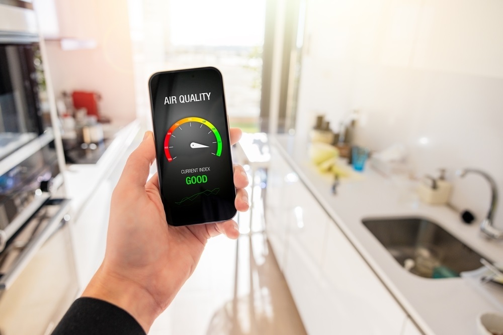 Person in kitchen at home viewing air quality index on mobile phone