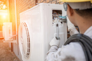 A technician repairing an outdoor air conditioning unit