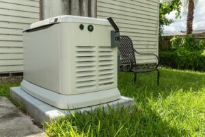 Backup generator installed on a concrete slab in a grassy backyard next to a house