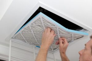 Man replacing an air filter in a ceiling vent for home HVAC maintenance
