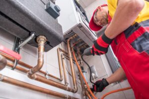 Professional technician in red overalls repairing or installing a gas boiler system