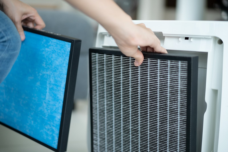 Person replacing air purifier filters to maintain indoor air quality