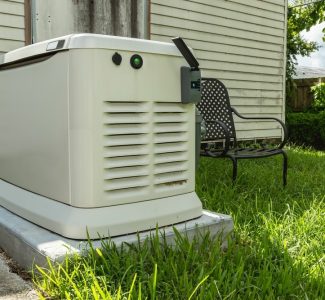 Backup generator installed on a concrete slab in a grassy backyard next to a house