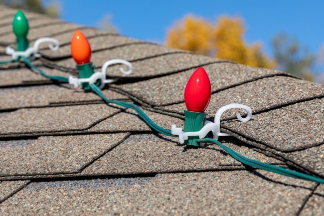 Hanging Christmas string lights on shingles of roof